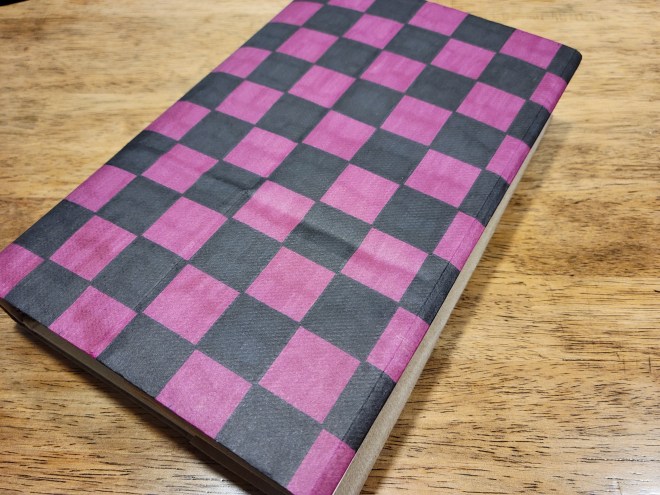 Book covered in paper bag colored with pink and black checks