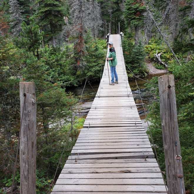 Woman hiking across a manmade bridge in the woods