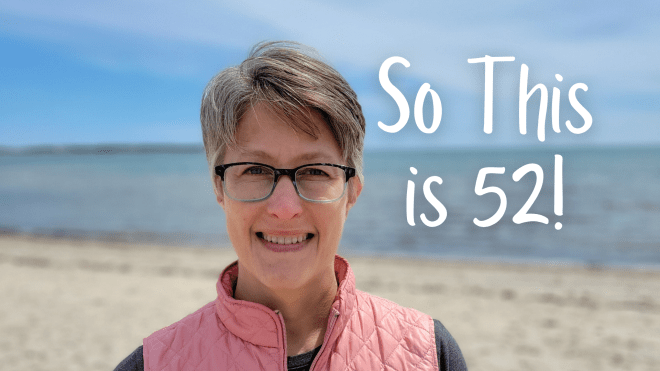 Woman wearing glasses and a pink vest standing on a beach