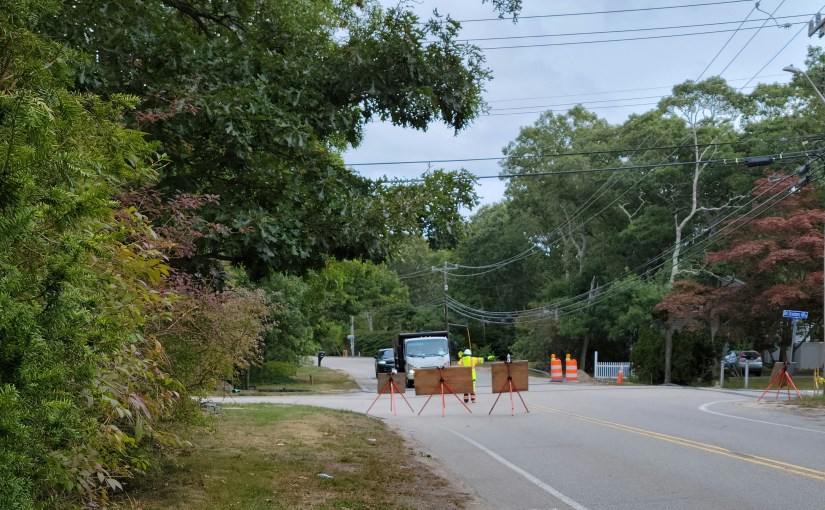 Road blocked by construction signs and someone directing traffic