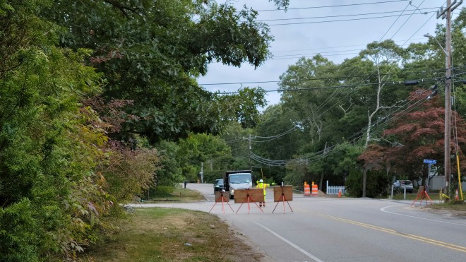 Road blocked by construction signs and someone directing traffic