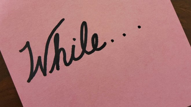 The word "while" written in cursive on pink paper