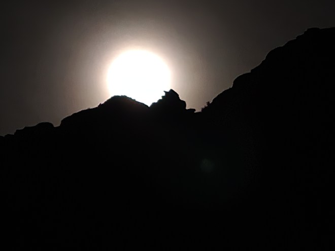 Moon resting atop dark canyon wall