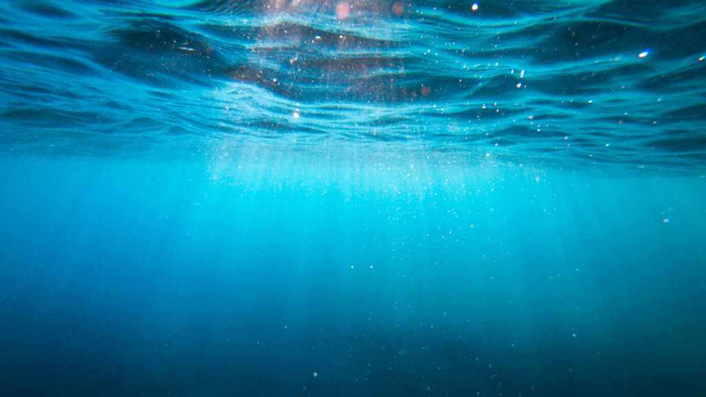 Underwater view of light streaming down into a blue ocean