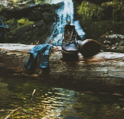 Hiking boots and wet socks sitting on a log over a stream